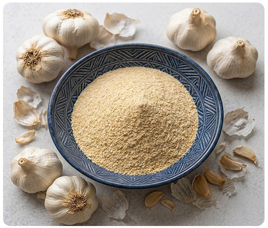 Bowl of premium garlic powder surrounded by fresh garlic bulbs and cloves, showcasing Food and Faith's 100% single ingredient garlic powder for everyday cooking and rich natural flavor.
